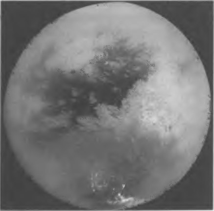 Рис. 8.13. Поверхность Титана, сфотографированная зондом «Кассини» 26 октября 2004 г. с расстояний от 300 тыс. до 650 тыс. км. Это мозаика из 9 лучших снимков, наиболее четко демонстрирующих детали поверхности, не закрытые в момент съемки облаками и туманом. Наилучшее разрешение в центре диска (координаты — 15° ю. ш. и 156° з. д.) — 2 км/пиксел. Внизу отчетливо видны яркие облака вблизи южного полюса. Правее центра — светлая область Ксанаду, левее и выше центра — темная область Шангрила